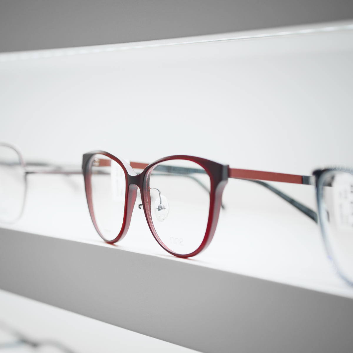 Side view of dark red glasses – elegant design with blurred background of other models