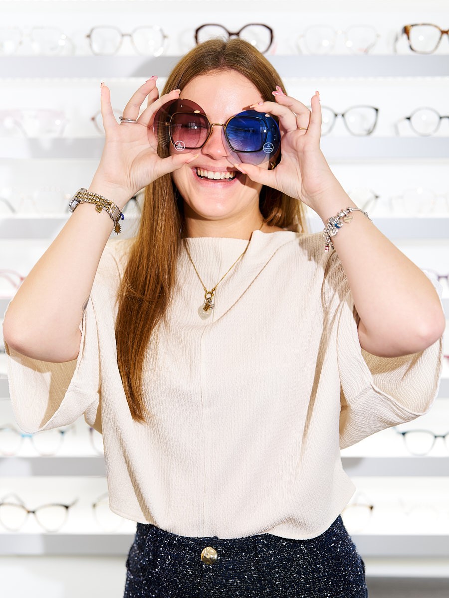Optical team member presenting modern sunglasses and individual eyewear styles in a professional optical store.