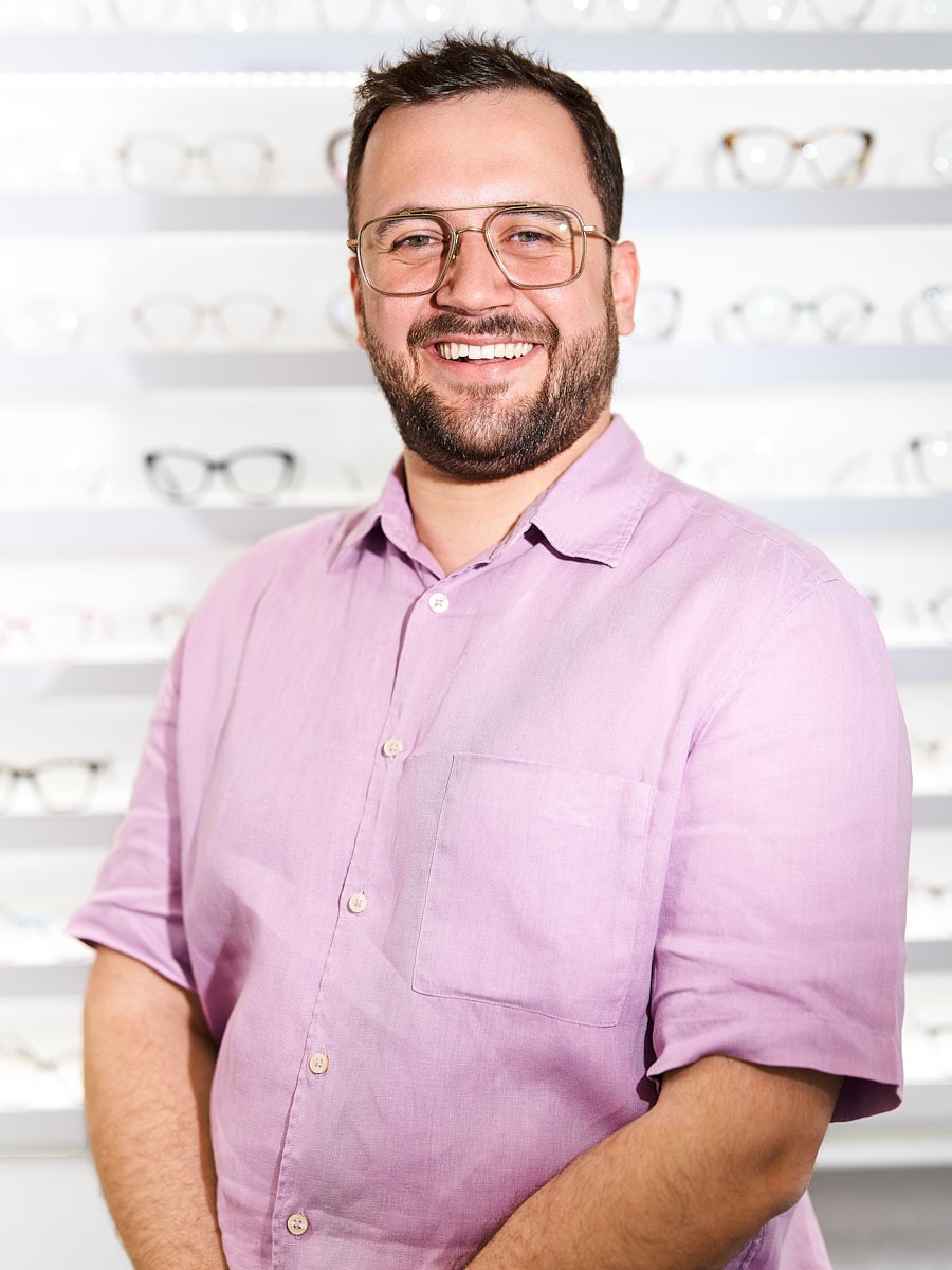 Managing director and optician wearing modern glasses in an optical store offering personal eyewear advice.