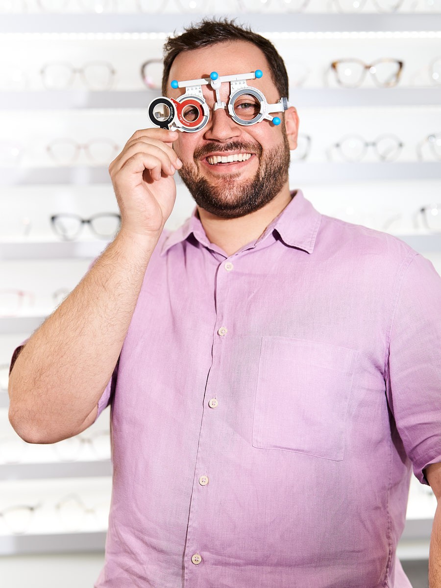 Managing director and optician with trial frames for precise vision testing and professional optical care.