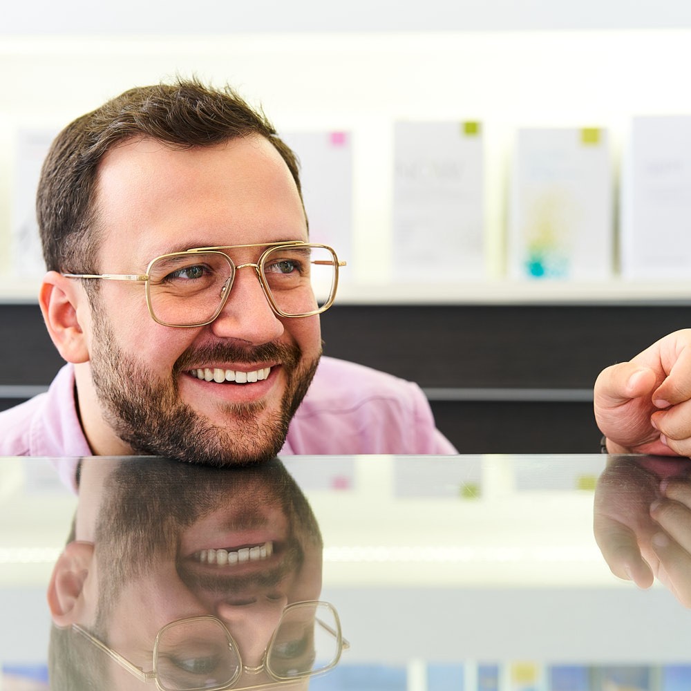 Optician providing personal eyewear advice and helping customers choose the perfect frames in an optical store.